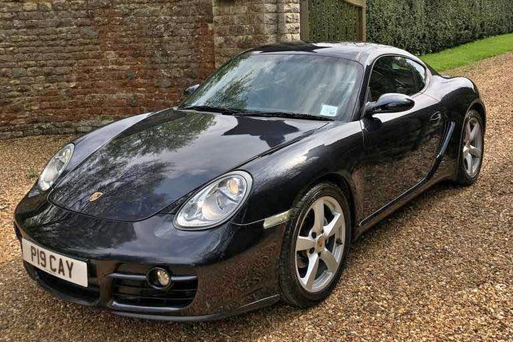 Black Porsche Cayman parked in front of the gates of a wedding venue